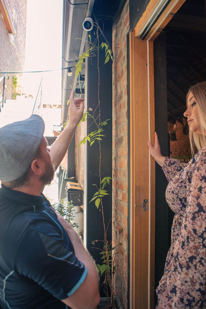 Blake pointing out a camera with a client at the doorway